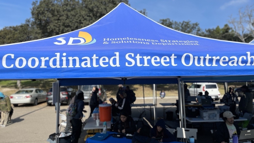 Coordinated Street Outreach City tent in a parking lot with tables set under the tent to help with outreach services.